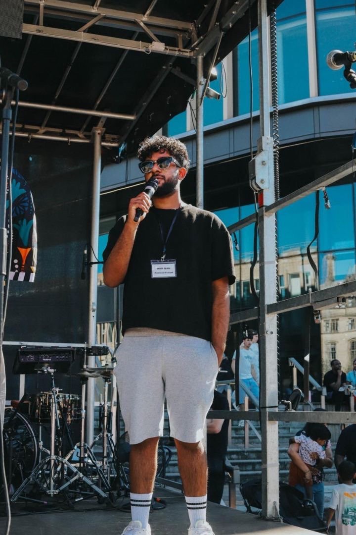 Amos Bashir speaking into a microphone on an outdoor stage in Bradford
